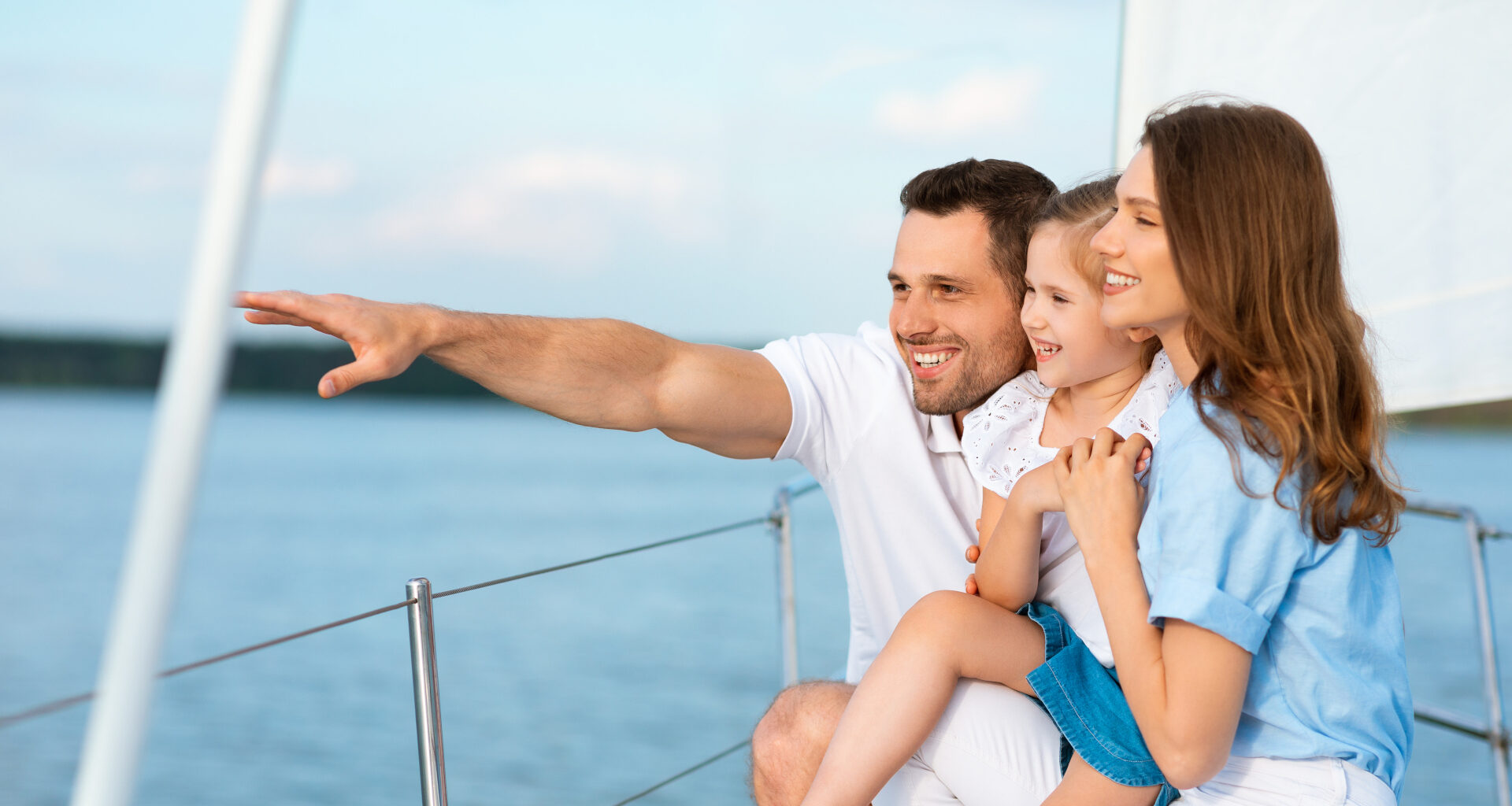 A family of three sailing on a boat on a sunny day.