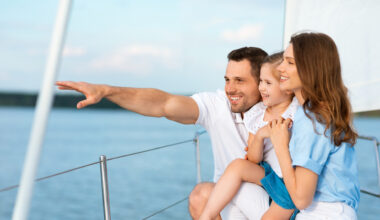 A family of three sailing on a boat on a sunny day.