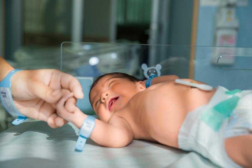 father-holds-hand-newly-born-babe-diapers