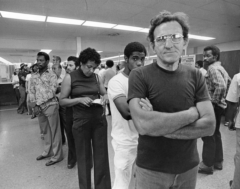 black and white photo of people in a line at a job fair