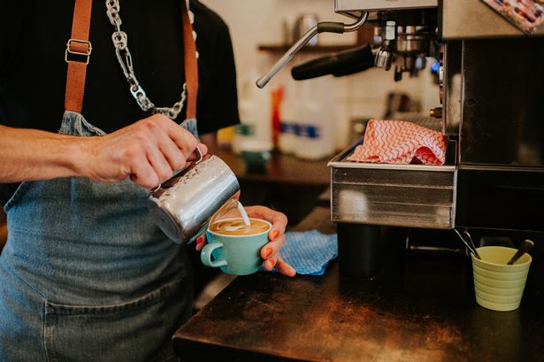 A close-up of a barista making a delicious latte coffee with milk.