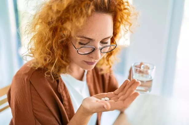 Woman Holding Water and Pill at Home
