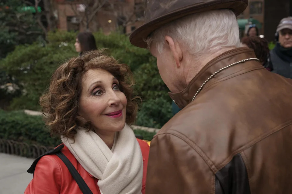 Andrea Martin and Steve Martin share a conversation outdoors. Andrea wears a scarf and leather jacket, while Steve wears a leather jacket and hat
