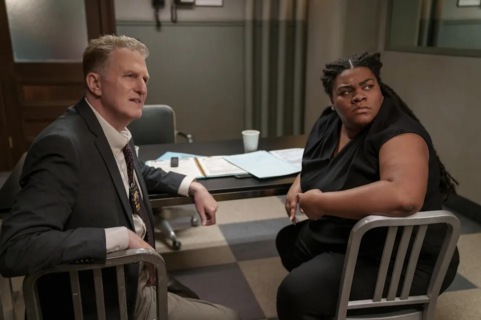 Michael Rapaport and Da'Vine Joy Randolph sitting in an interrogation room, both looking intently at someone off-camera