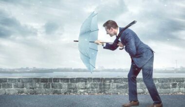 Businessman with an umbrella is facing strong headwind