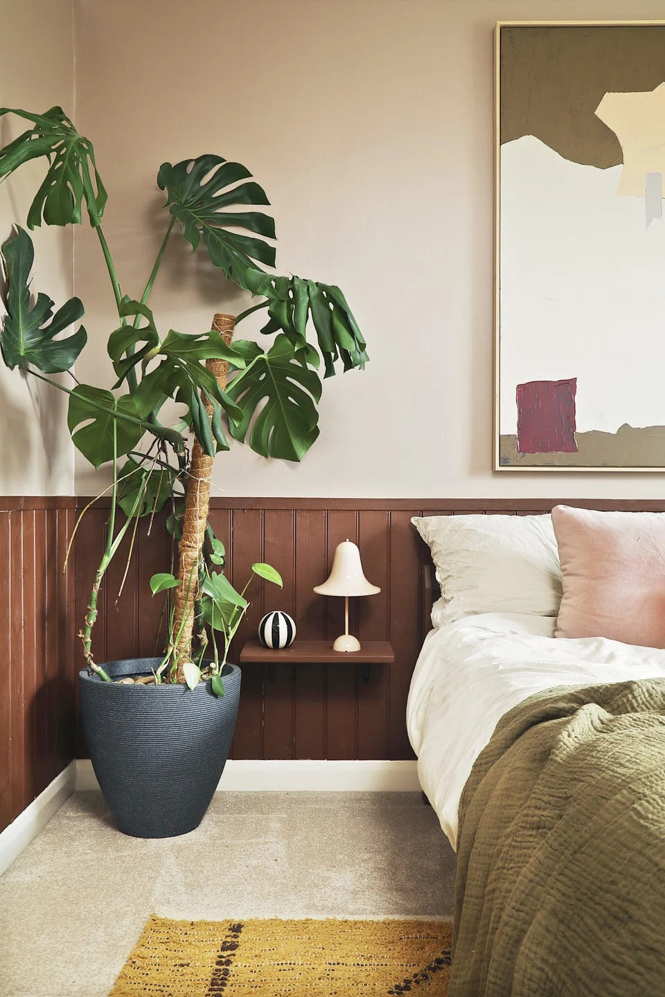 bedroom with large plant and panelled wall
