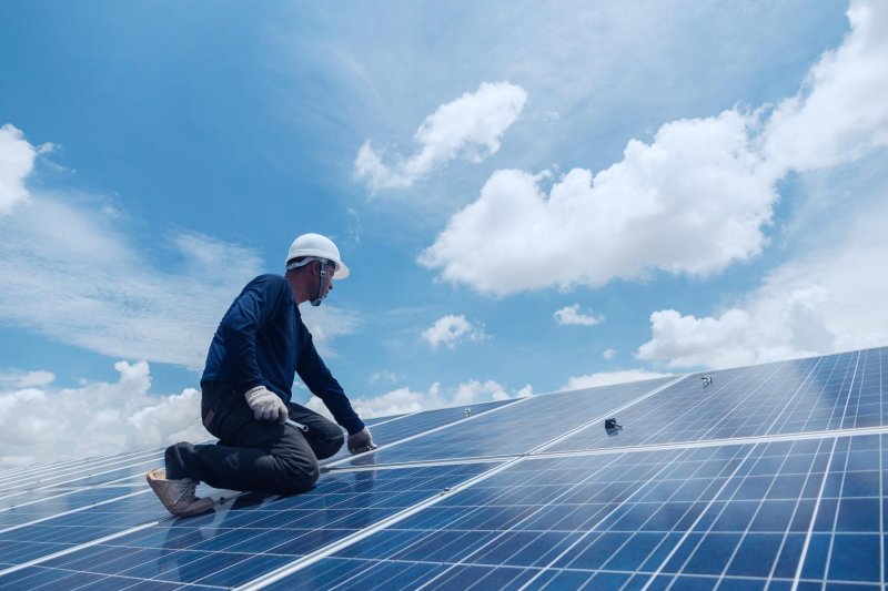 An engineer replaces a solar panel on the roof of a solar power plant. The community solar cell project is one of three projects the government aims to push forward to completion by the end of this year.