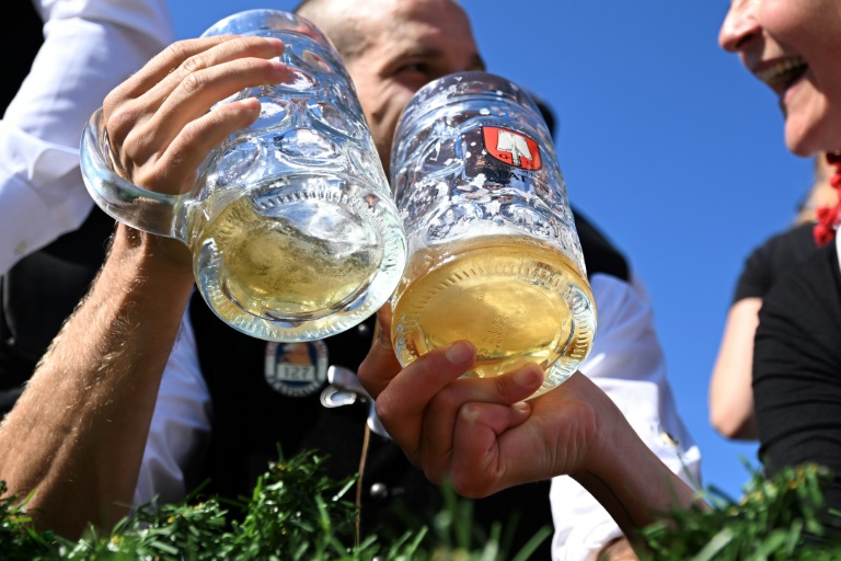 Revellers wearing traditional Bavarian costumes cheer with their beer mugs during the costume parade