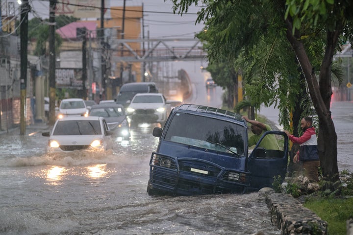 People abandon a car on an impassable street flooded by rains caused by Tropical Storm Melissa in Santo Domingo, Dominican Republic, Friday, Oct. 24, 2025. (AP Photo/Ricardo Hernandez)