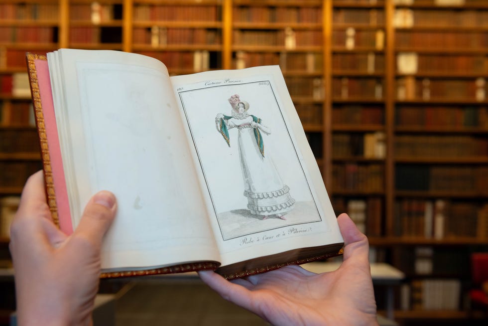 Illustration of a historical dress in a book held by a person