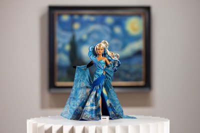 A Barbie in a Starry Night-inspired gown standing before the painting, which is out of focus.