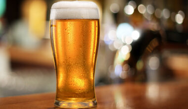 Glass of chilled beer on wooden bar table.
