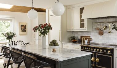 Kitchen with large center island with dark cabinets and white counter top. On the back wall there's a stove.
