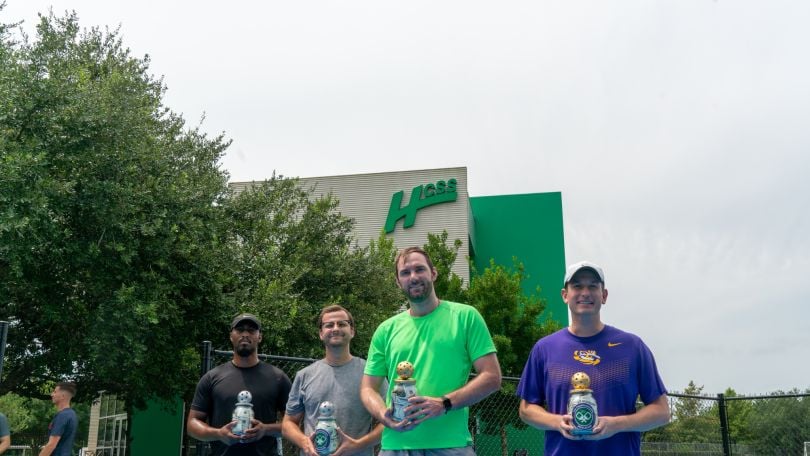 Several HCSS employees pose outside with trophies