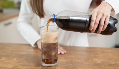 woman pouring fizzy cola soda into a glass of ice