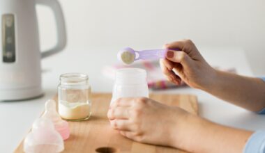 Mother hands with baby bottle and scoop preparing infant formula milk