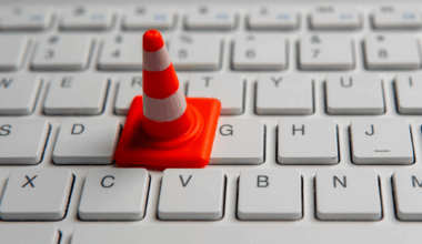 A small orange traffic cone placed on a white computer keyboard.