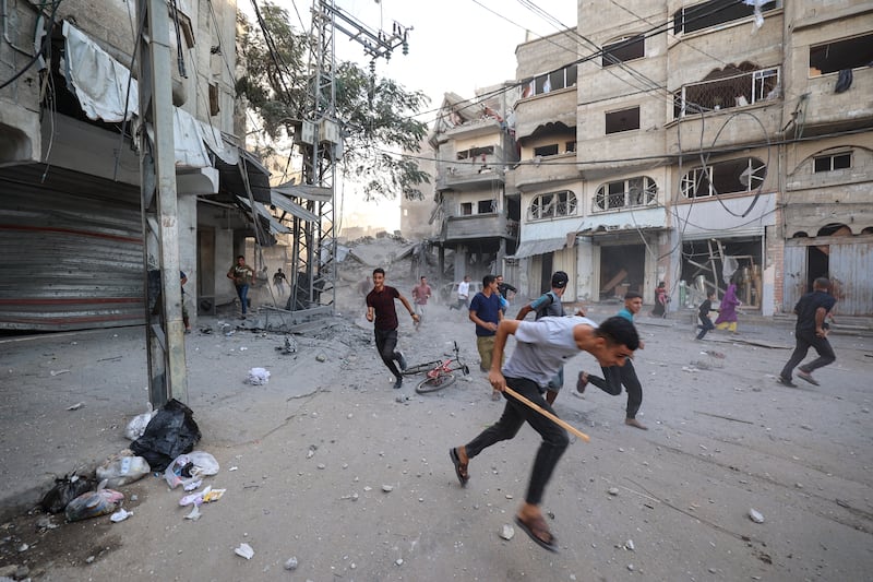 People run for cover following an Israeli strike that targeted a building in the Bureij camp for Palestinian refugees in the central Gaza Strip. Photograph: EYAD BABA/AFP via Getty Images          