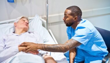 Male nurse comforting patient in hospital bed