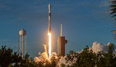 SpaceX Falcon rocket launches from the Kennedy Space Center with flames and smoke billowing as it lifts off the launch pad.