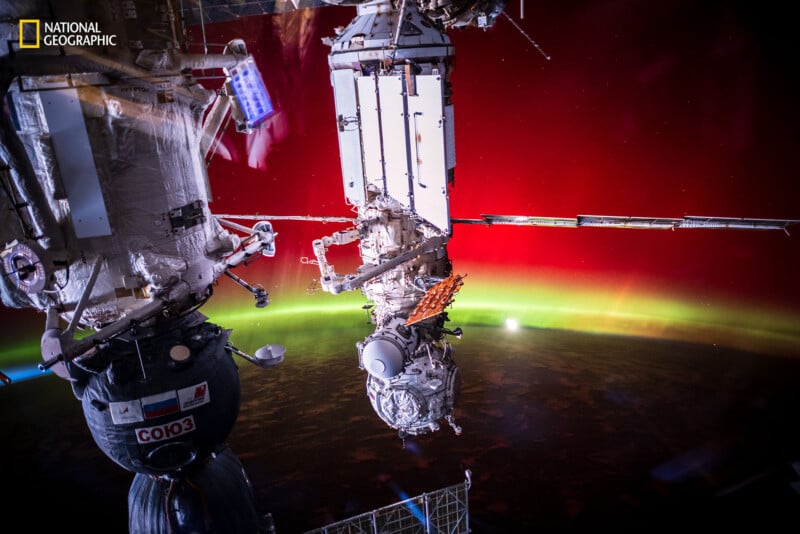 View of a spacecraft docked to the International Space Station, with glowing green and red auroras visible over Earth's horizon in the background. National Geographic logo in the top left corner.