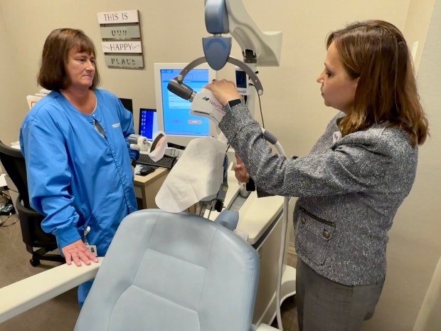 Registered nurse Gina Panka, left, and Dr. Mona Lal adjust a machine used for transcranial magnetic stimulation, or TMS, to help patients with treatment-resistant depression at Northwestern Medicine Palos Hospital in Palos Park. (Northwestern Medicine)