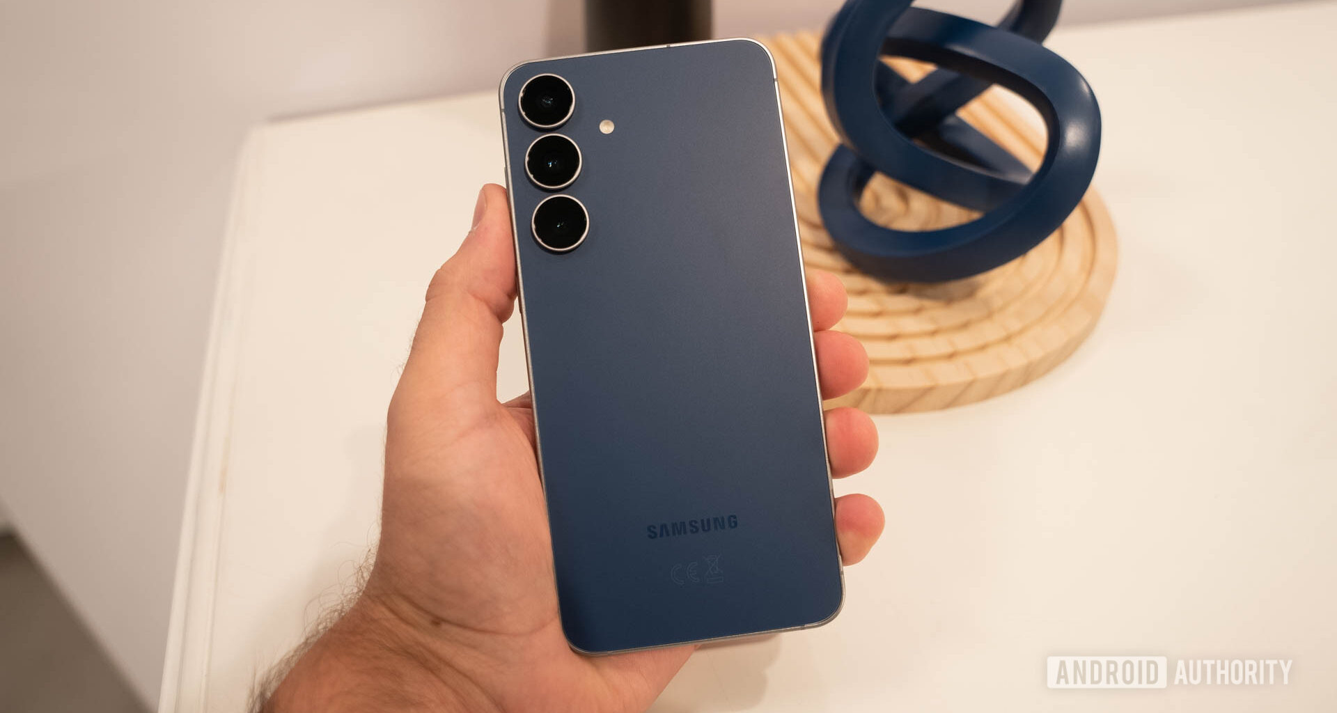 Samsung Galaxy S25 FE in Navy in man's hand showing back of phone