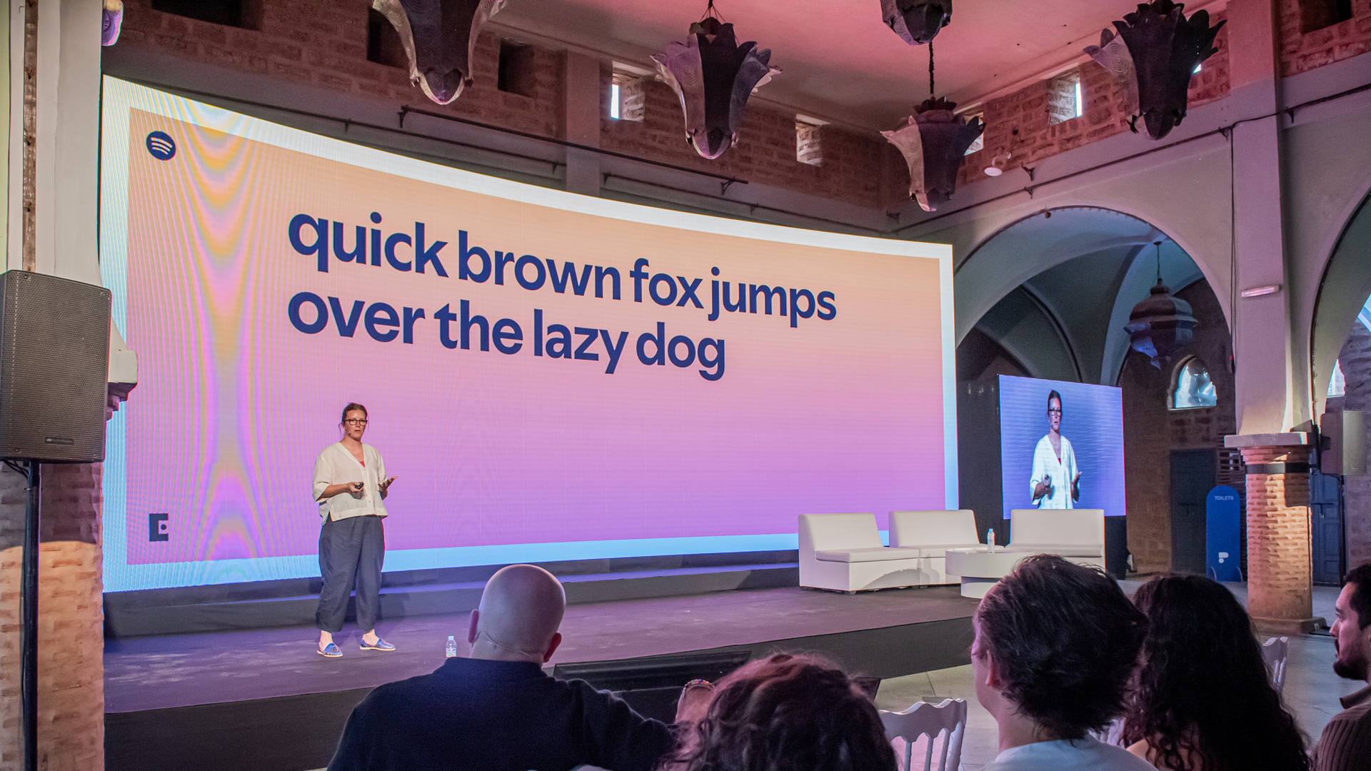 Bianca Berning on stage at Paradigms 2025 conference with a screen that says 'quick brown fox jumps over the lazy dog'