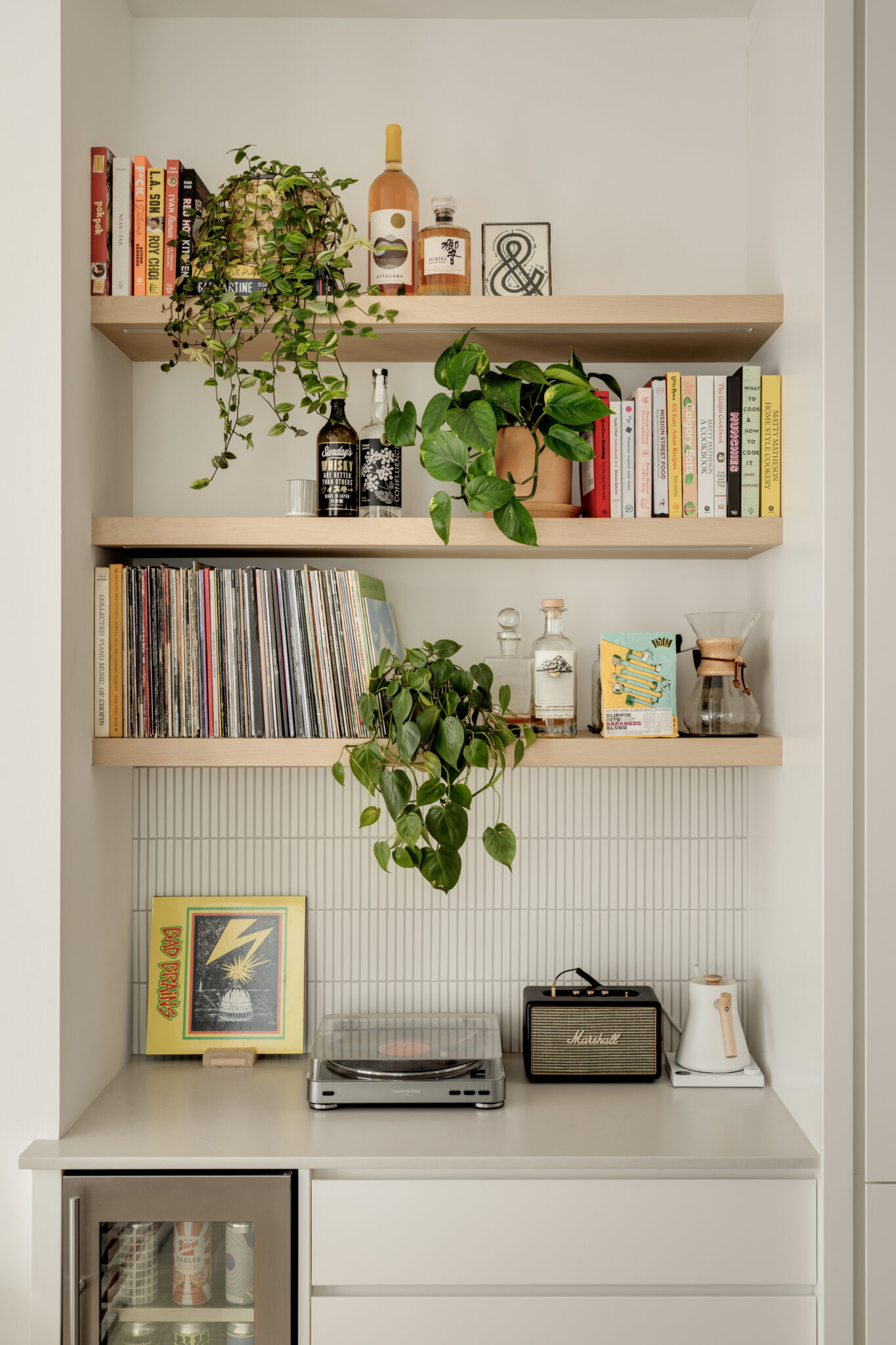 A bar nook with books, vinyl records, a vinyl player and plants.