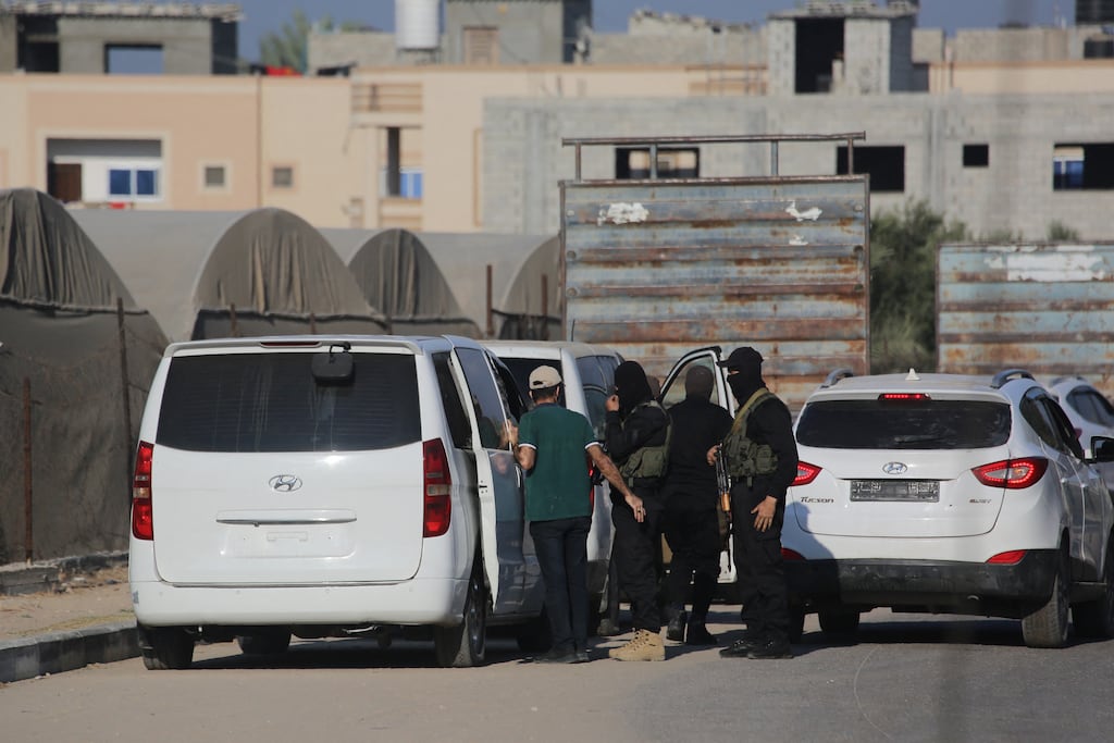 Members of Hamas military wing, Al-Qassam Brigades, stand guard next to vehicles carrying released Israeli hostages on a main road in Deir al-Balah in the central Gaza strip on Monday. Photograph: Bashar Taleb/AFP/Getty