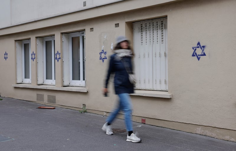A woman walks along a building whose facade is covered with Stars of David painted during the night, in the Alesia district of Paris, in October 2023. Photograph: Geoffroy Van der Hasselt/AFP via Getty Images