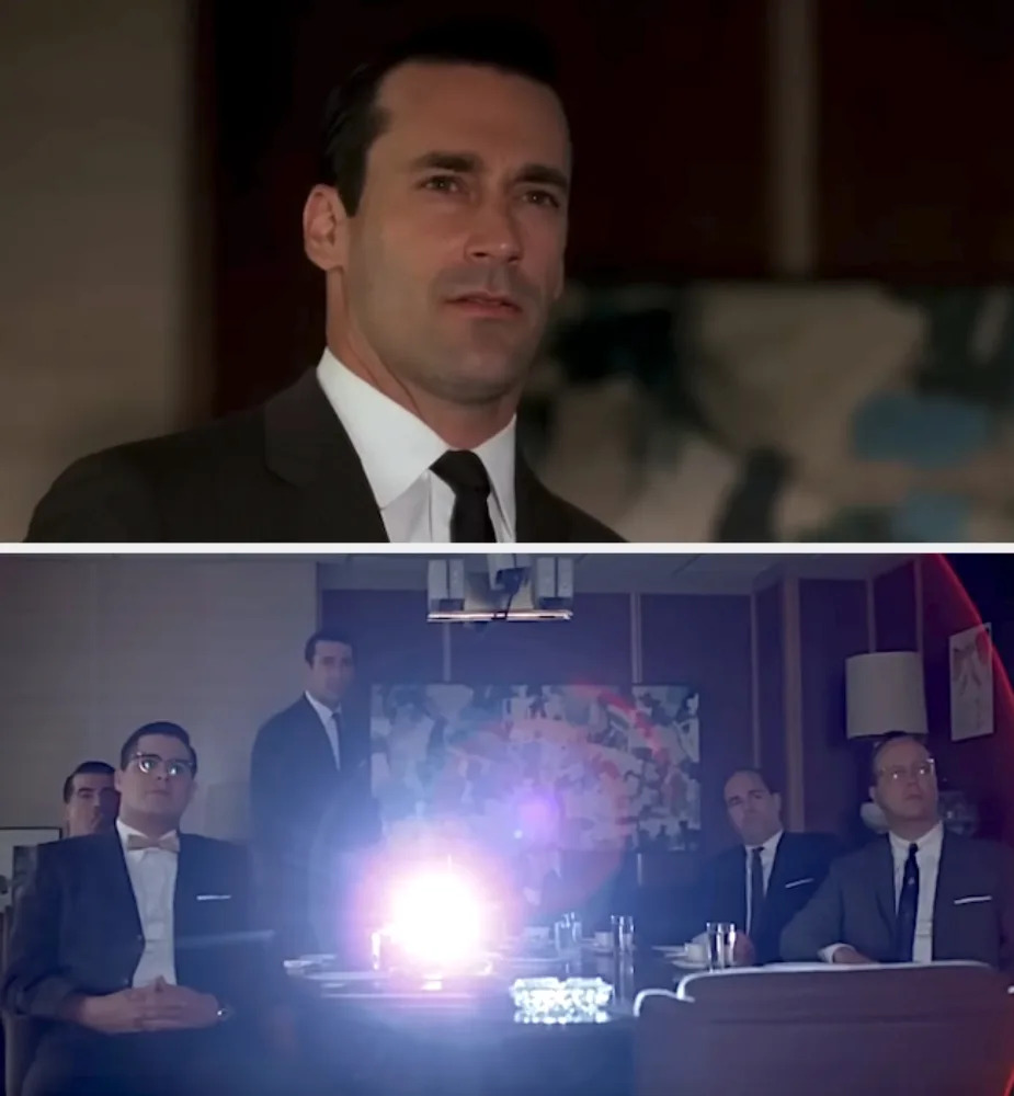 A man in a business suit presents to a captivated audience in a dimly lit meeting room