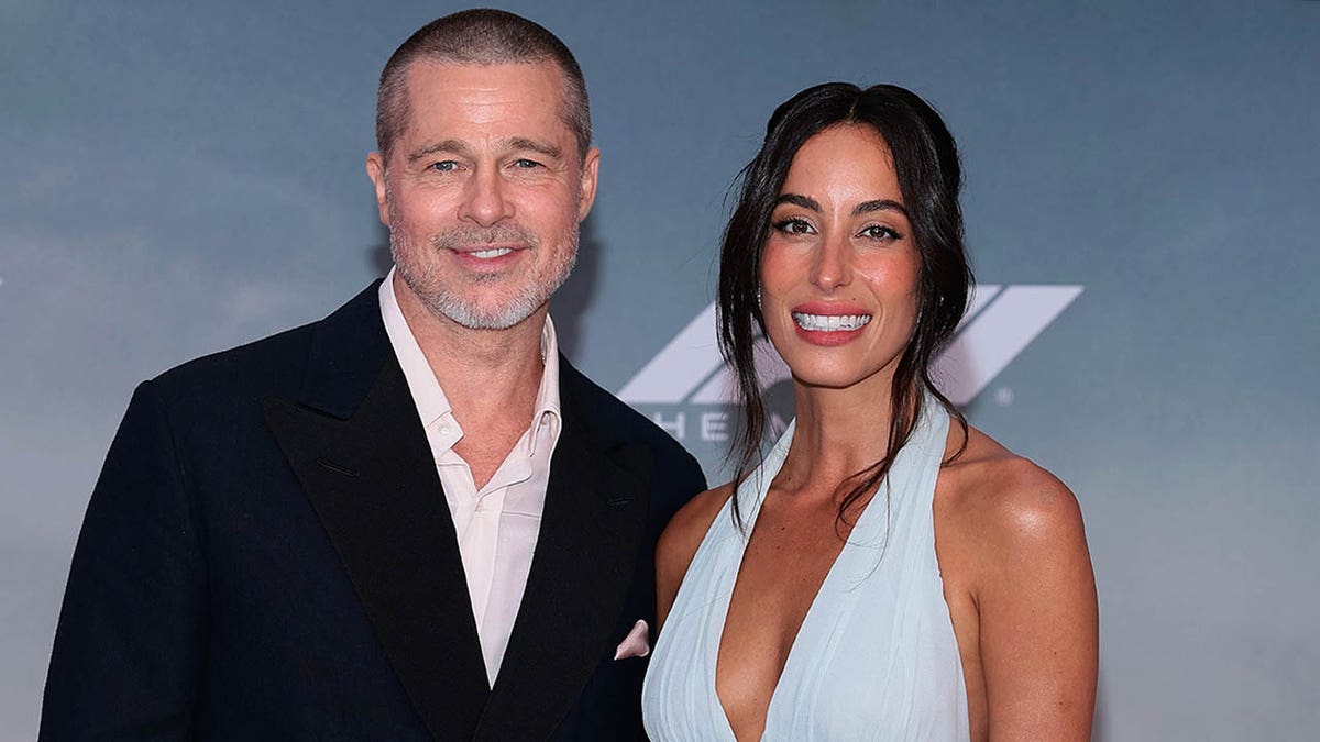 Brad Pitt and girlfriend Ines de Ramon smile and pose together on the red carpt at the F1 premiere. 