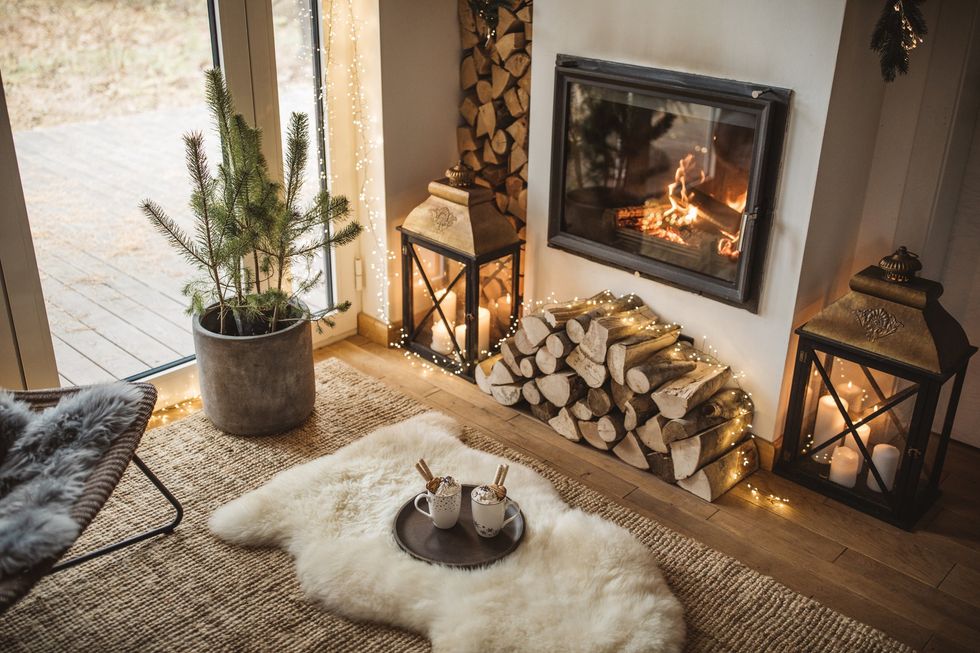 Cosy living room with fireplace, fur rug, candles, and houseplant