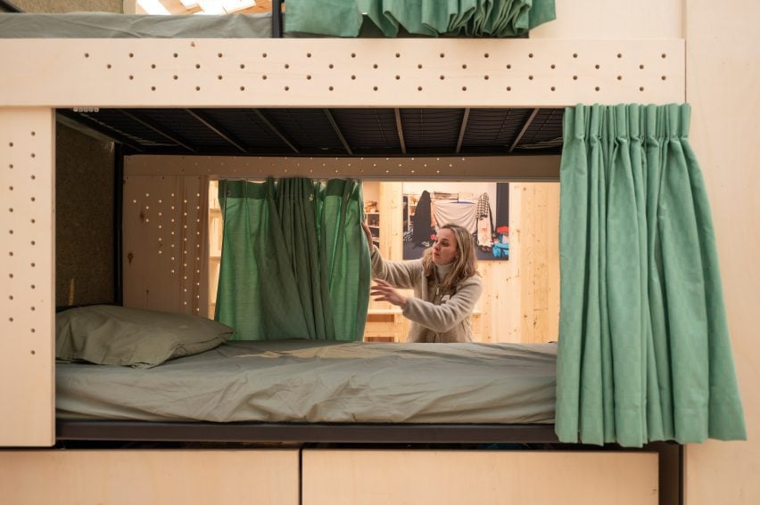 Photo of Anneloes de Koff adjusting the green privacy curtain around a De Wachtkamer bunk bed 