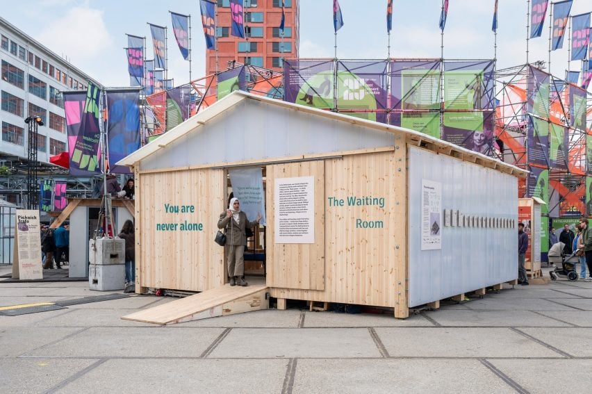 Exterior photo of the Wachtkamer pavilion at Dutch Design Week 2025, showing a gabled structure made of waste wood panels and polycarbonate panels