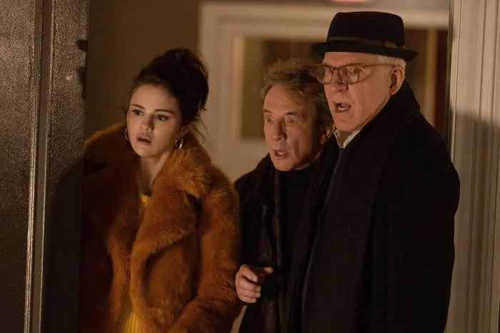 Selena Gomez, Martin Short, and Steve Martin standing together indoors, all looking surprised