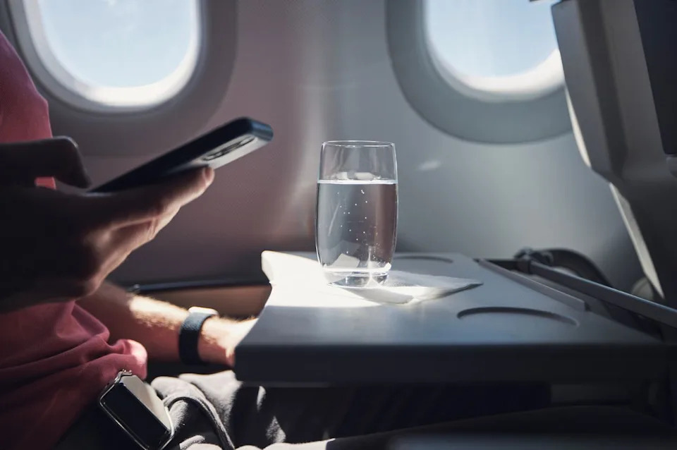 Chalabala/Getty Images A glass of water on an airplane tray table.
