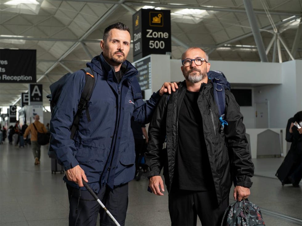 Hunted 2025 contestants Ste and Chris two men posing together at an airport terminal