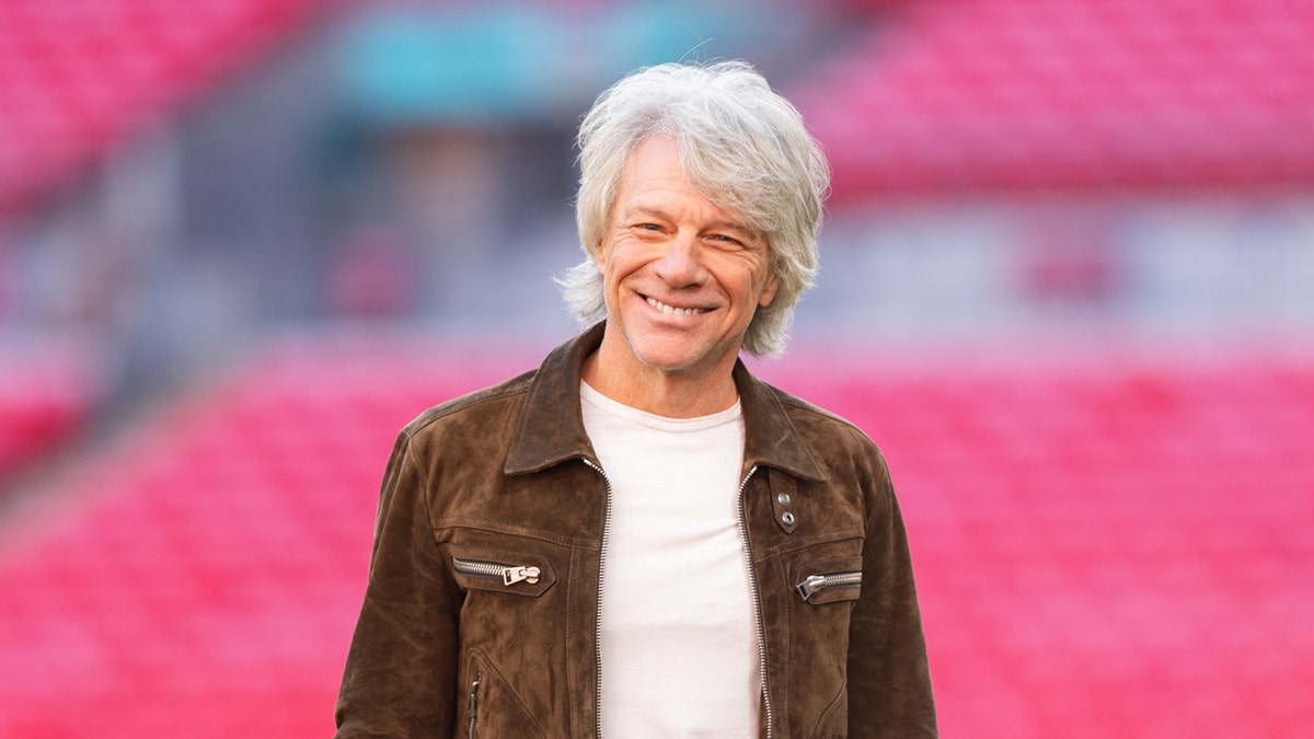Jon Bon Jovi stands in a stadium to announce his tour