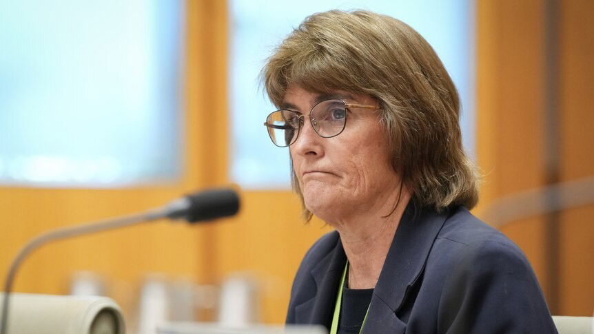Michele Bullock looks glum as she sits behind a microphone.