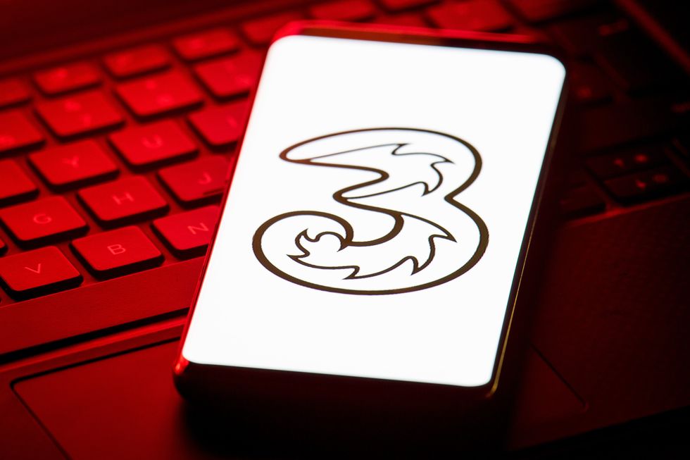 mobile phone pictured on a laptop keyboard with the three company logo on-screen