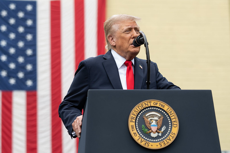 Donald Trump giving a speech from a lectern with the seal of the President of the United States and an American flag in the background.