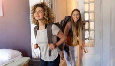 Two young women entering their apartment with backpacks on their backs.