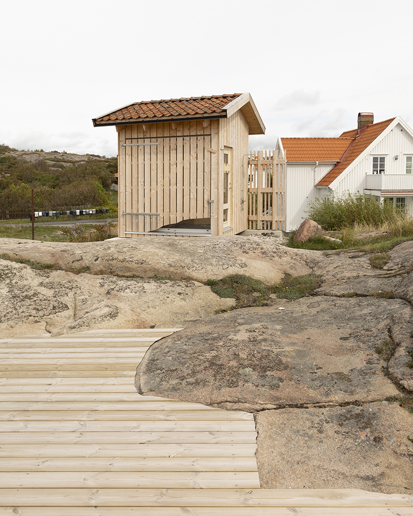 untreated wooden cladding wraps vernacular sauna sövall on sweden's rocky shoreline