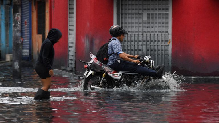 People travel through a flooded street in Santo Domingo, Dominican Republic. Pic: AP