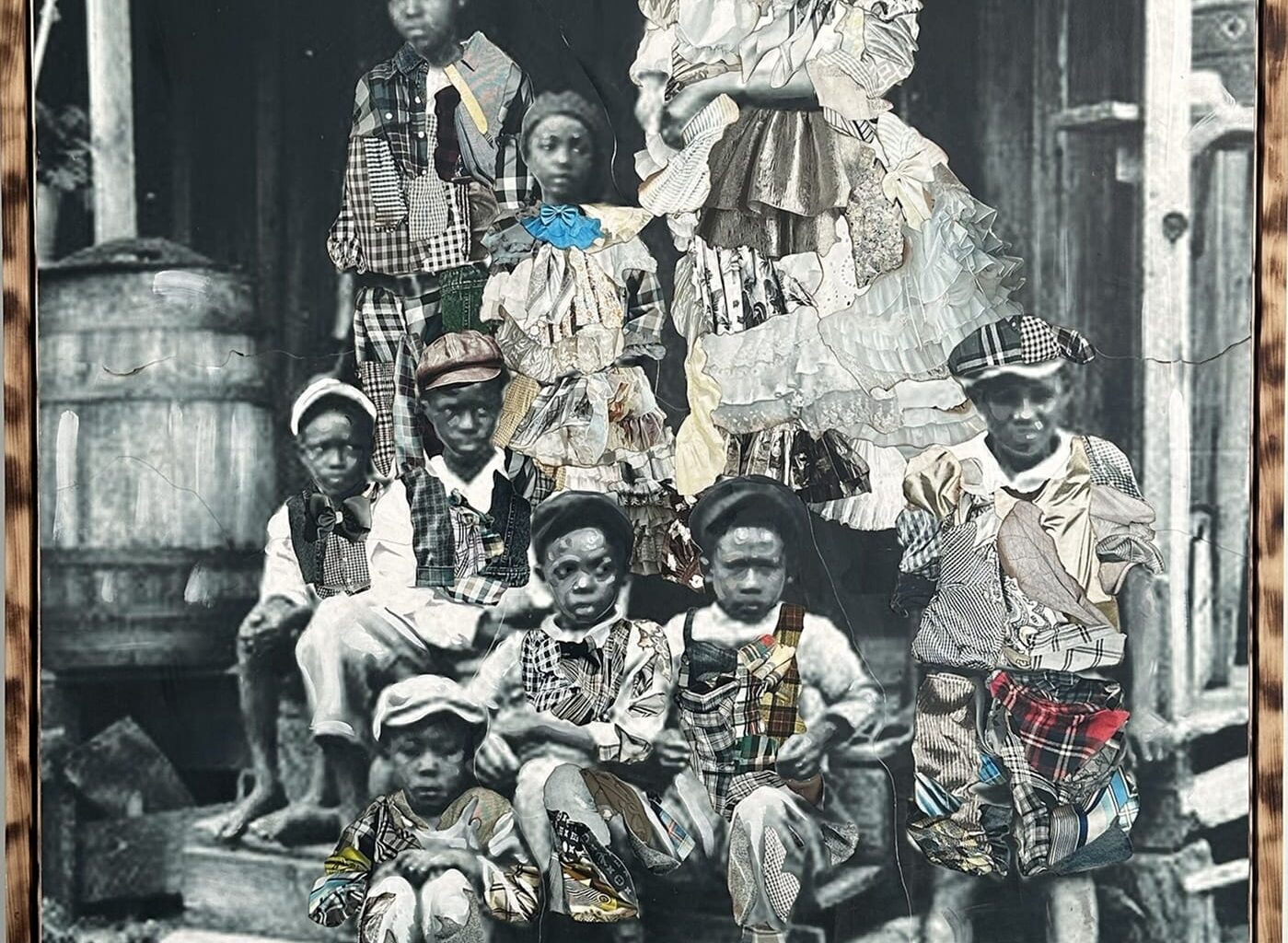 a framed portrait by Stan Squirewell, from an old photograph, of a large group or family seated on the porch a house, with colorful, patterned fabrics painted onto the image