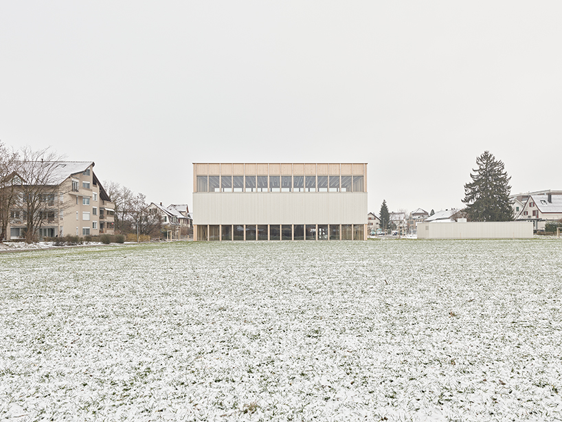 vertical timber construction shapes twin stacked sports halls in switzerland by kit