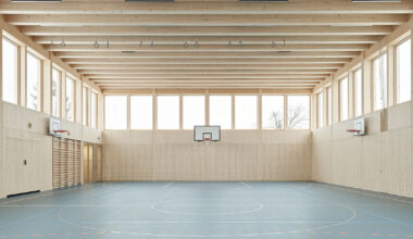 vertical timber construction shapes twin stacked sports halls in switzerland by kit