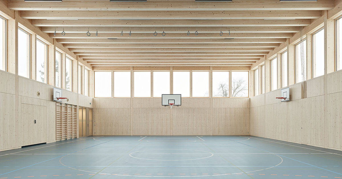 vertical timber construction shapes twin stacked sports halls in switzerland by kit